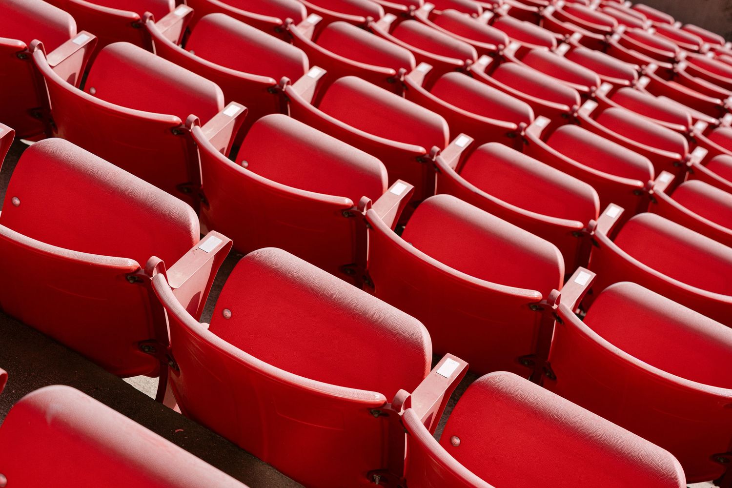 Empty red stadium seats arranged in curved rows create a vibrant geometric pattern at a sports venue.