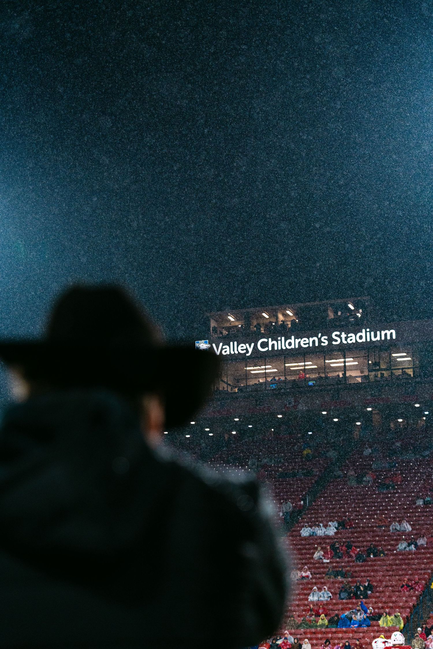 Valley Children's Stadium illuminated at night with scattered spectators in the stands and dark blue evening sky.