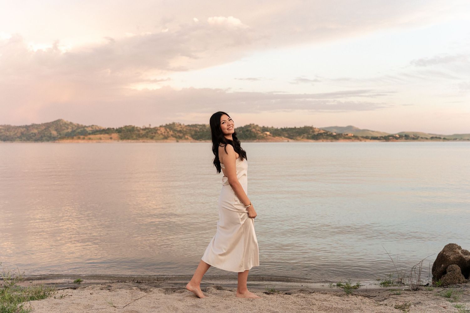 Person walking along scenic beach shoreline during sunset.