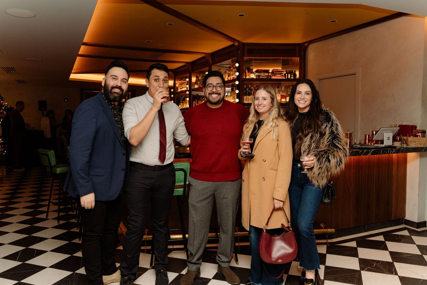 A social gathering in a venue with checkered floors and decorative lighting.