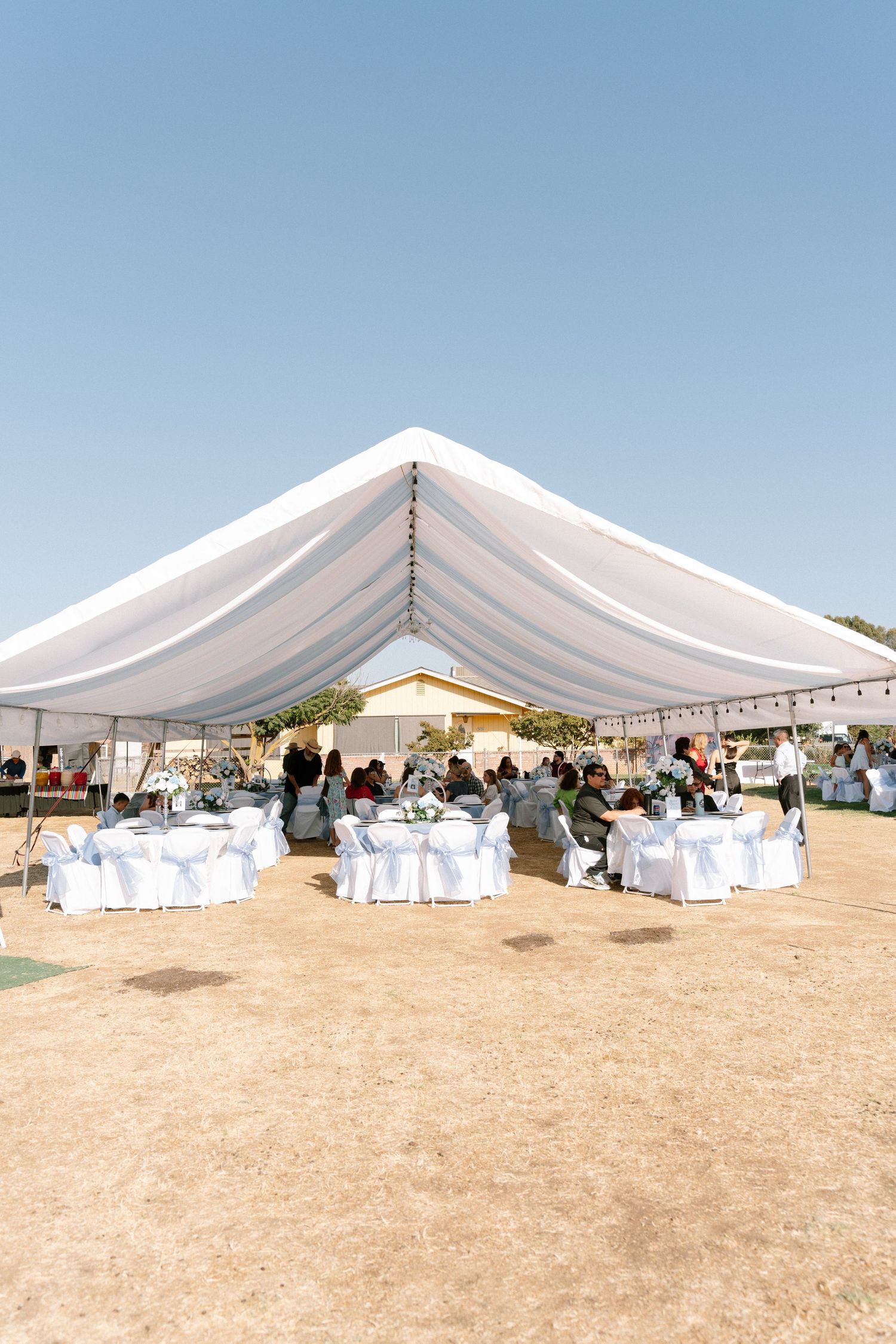 A large white wedding tent set up in an outdoor desert venue with guest seating.