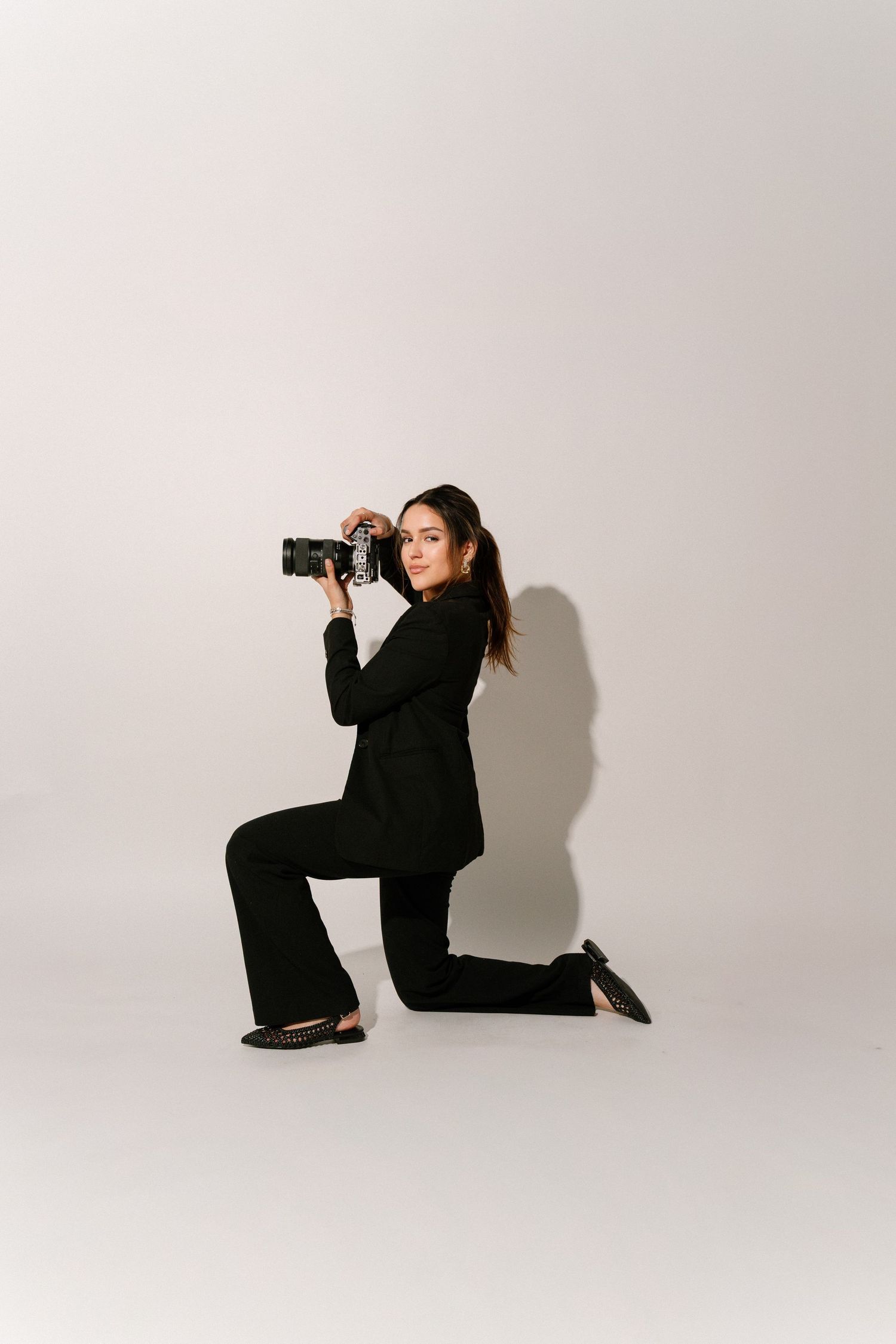 A person in black clothing poses dramatically in a series of artistic studio photographs against a white background.
