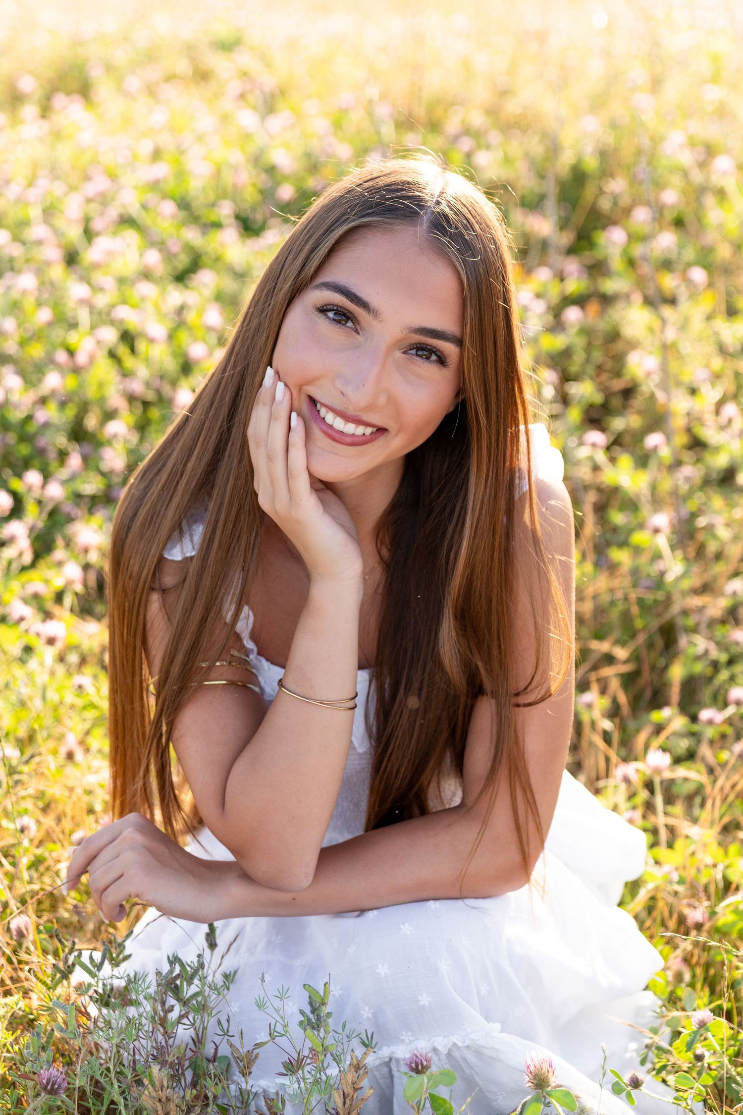 Portrait in white dress among sunlit wildflowers during golden hour.