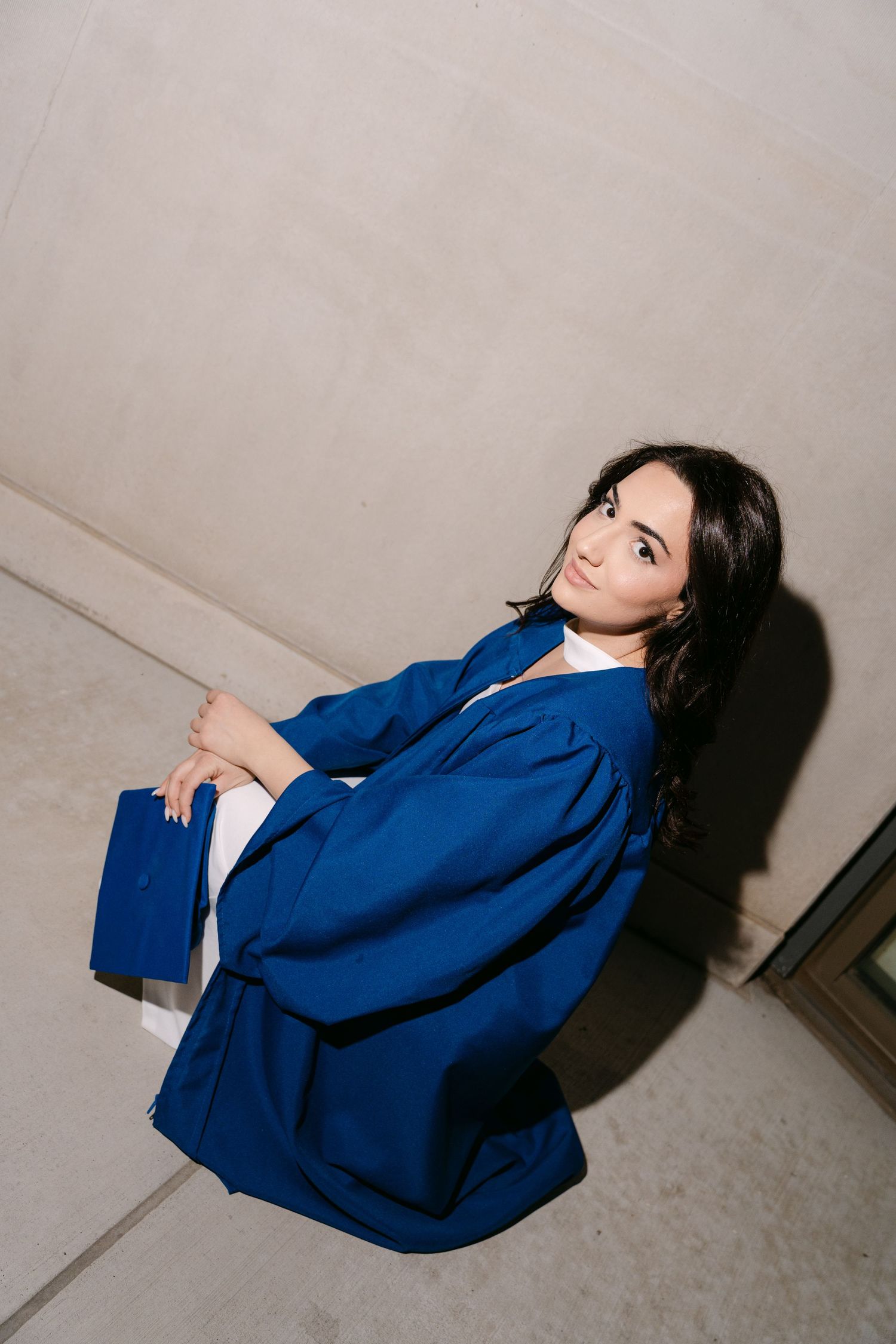 A person in a vibrant blue blazer poses dramatically against a neutral wall in a series of artistic fashion photographs.