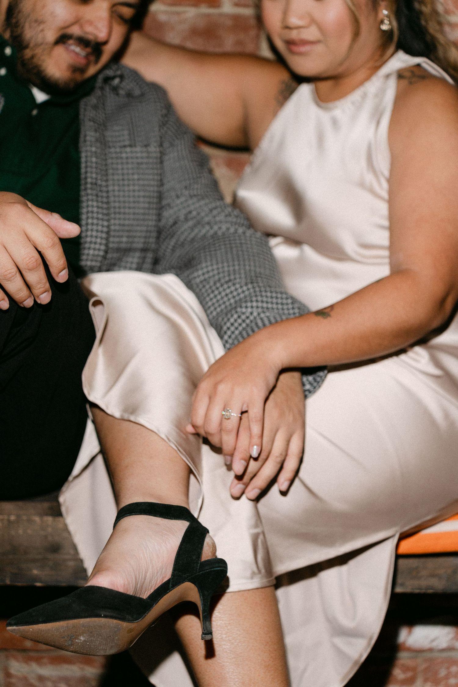 Close-up series showing hands wearing engagement ring with black socks and white dress against rustic background.