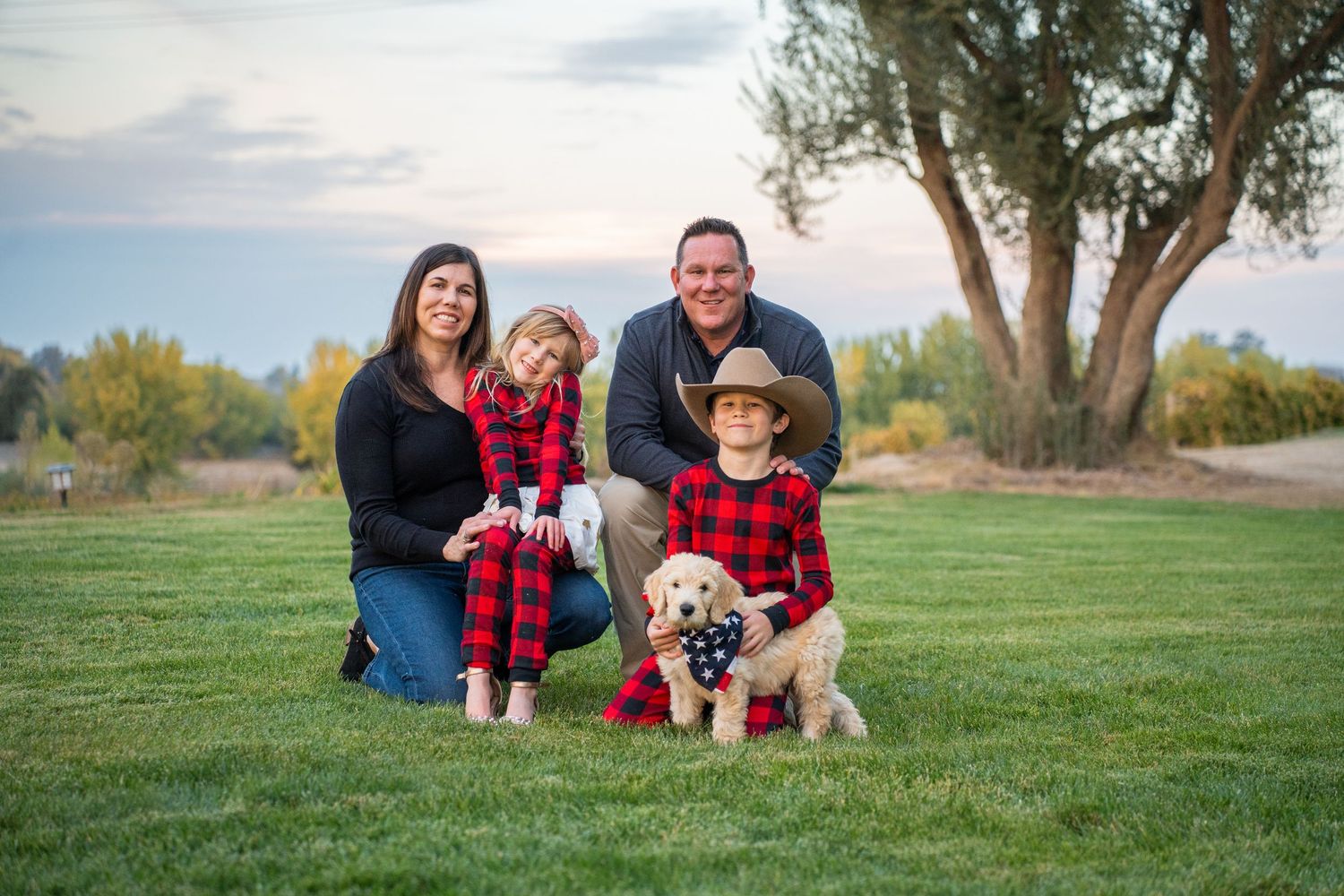 Family group photo session on green grass during golden hour.