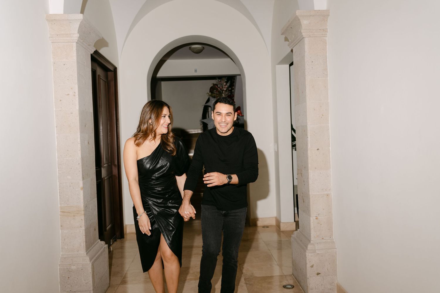 Two people walking together through an elegant arched hallway at night.