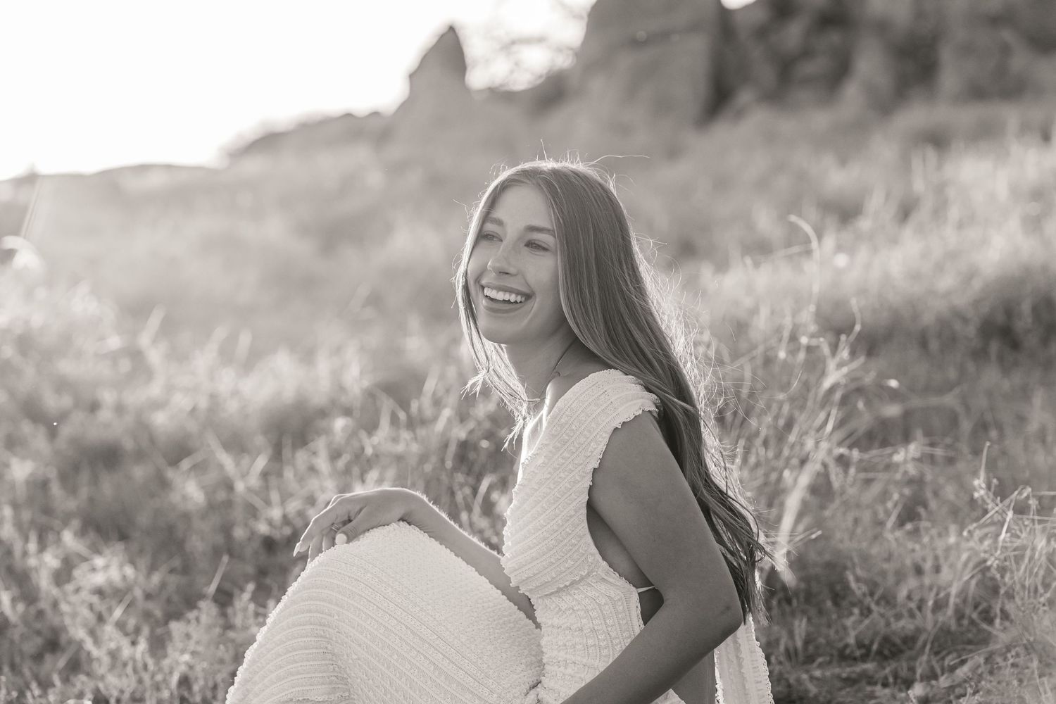 Black and white portrait of a woman laughing in a field.