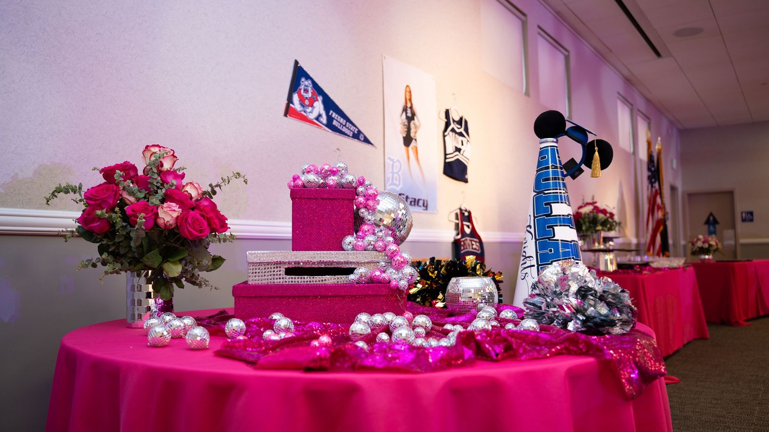 Pink and silver party decorations with balloons line tables at an elegant celebration.