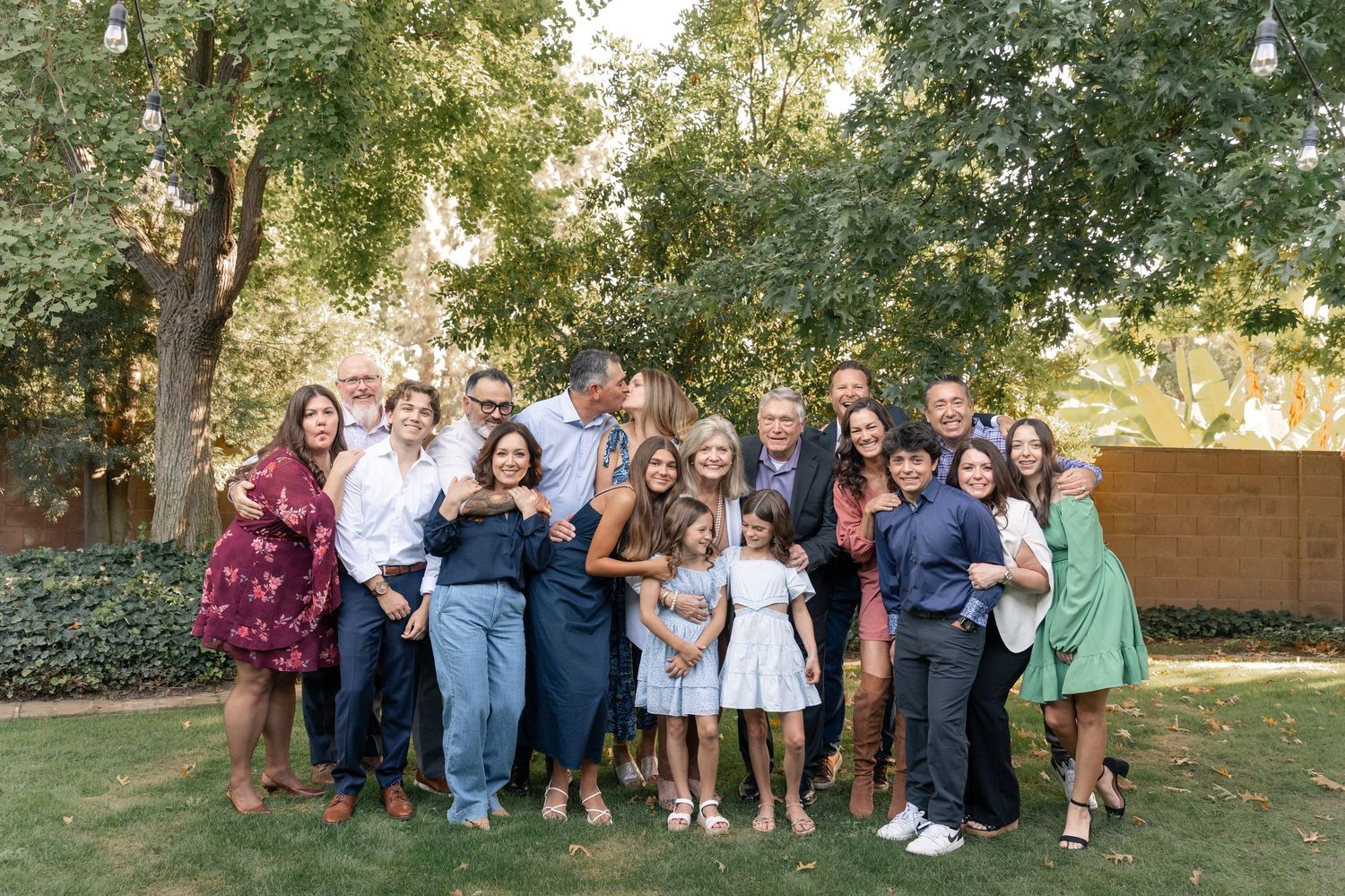Large group photo taken outdoors with trees and natural lighting.