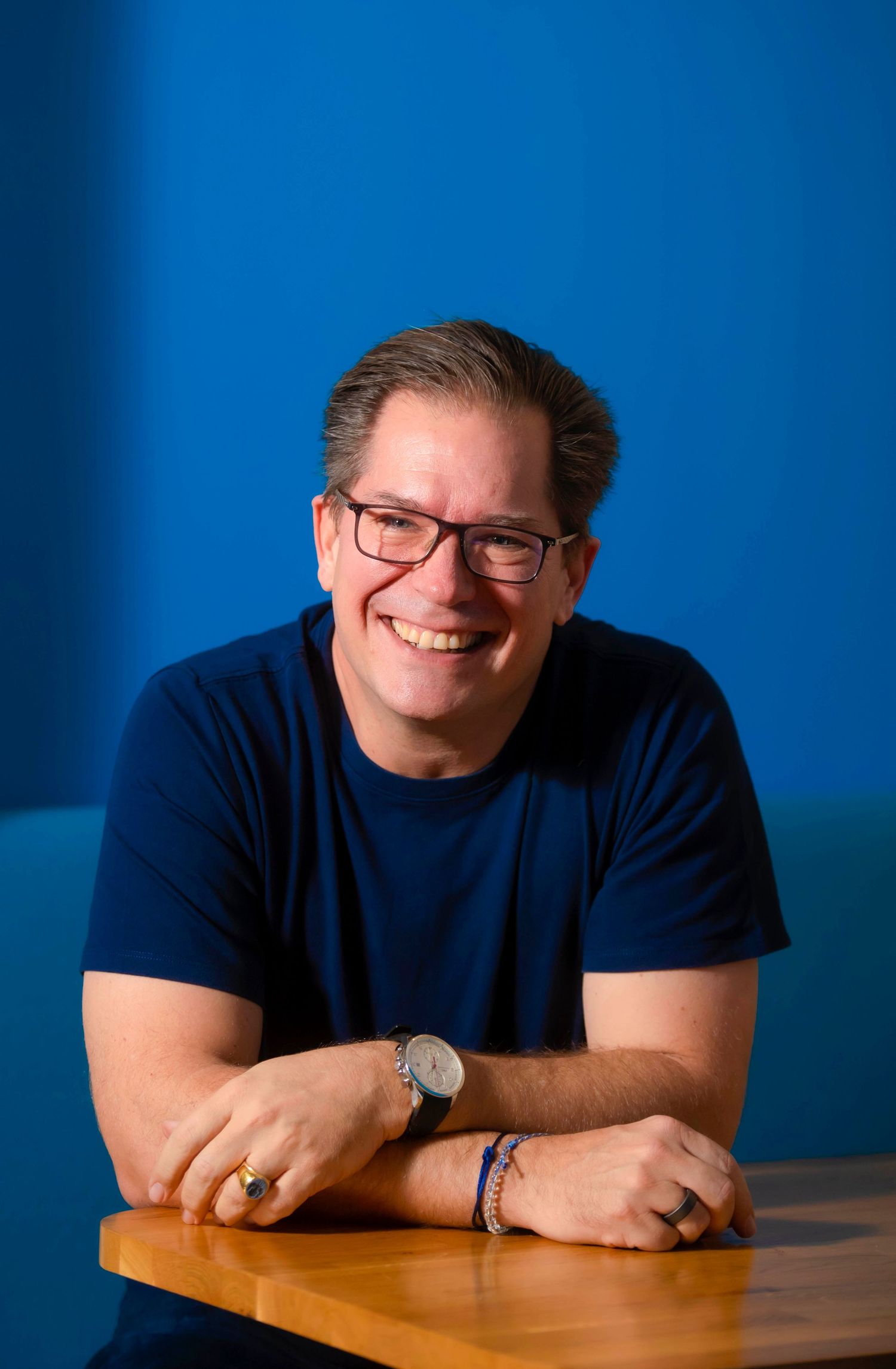 Person in navy shirt resting on wooden surface against blue backdrop. London Event Photographer