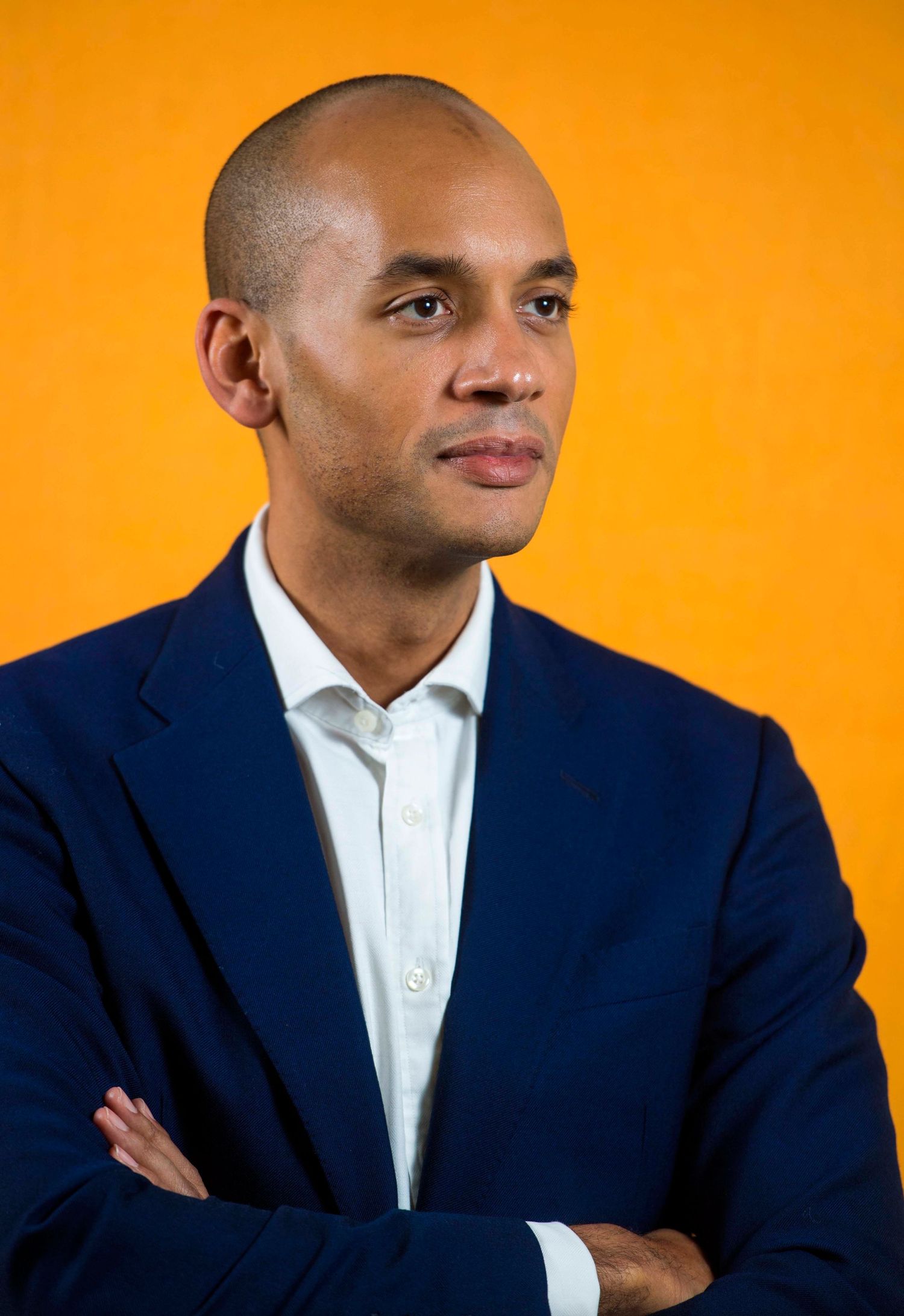 Professional portrait series against orange background showing confident pose in navy blazer and white shirt. London Event Photographer
