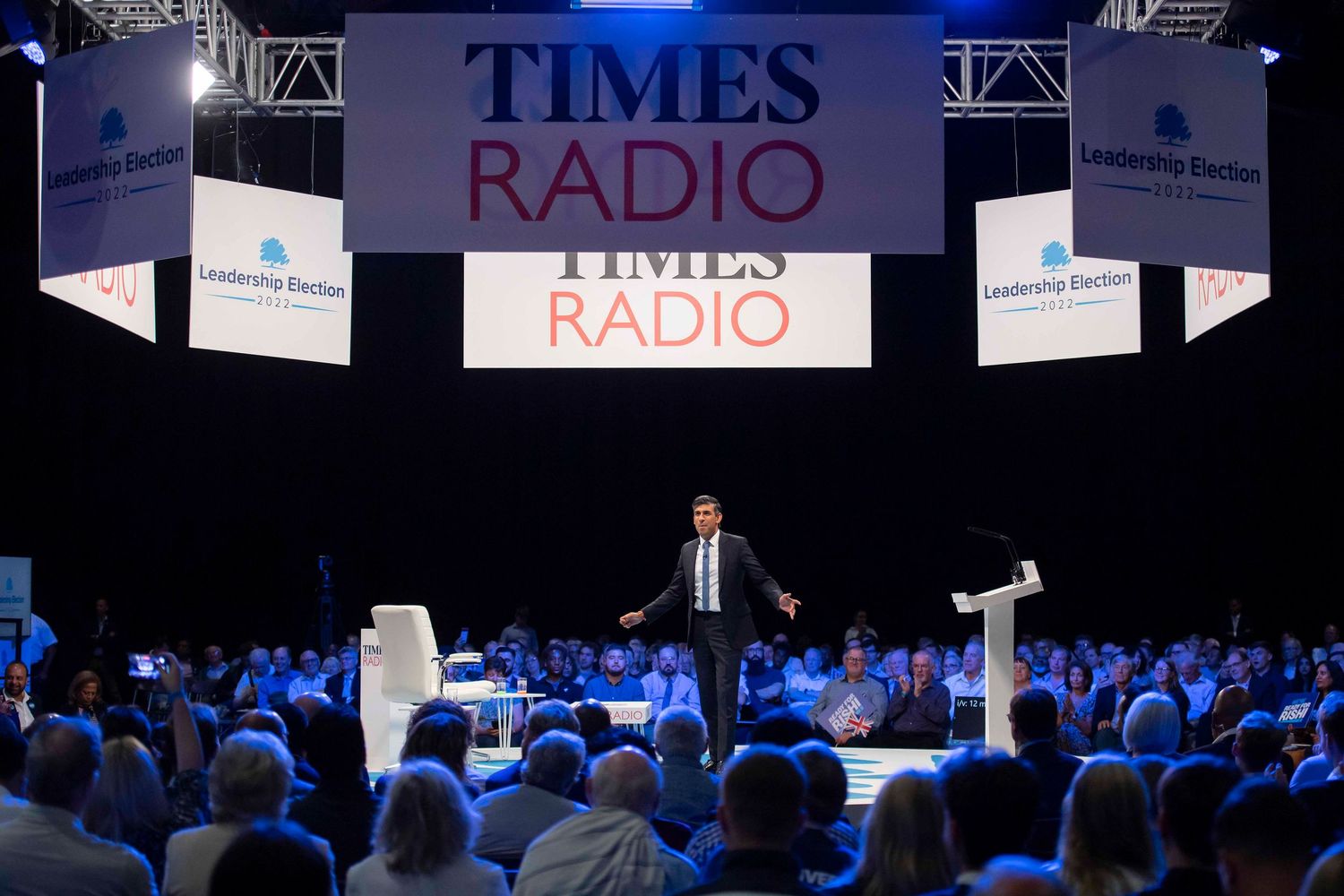Large conference auditorium with stage setup and audience under dramatic lighting. London Event Photographer