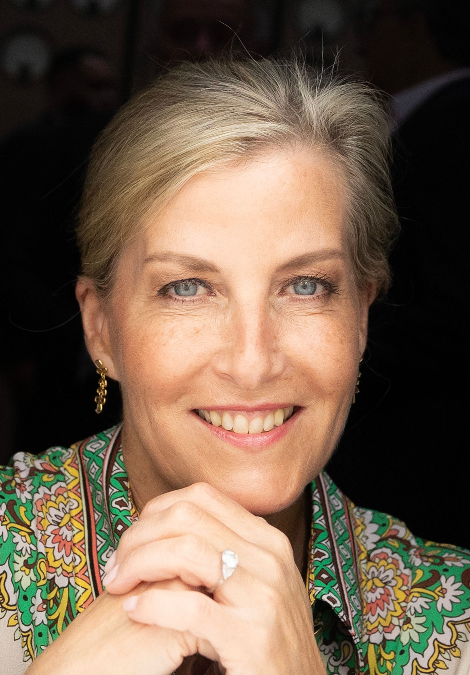 Portrait series showing warm expressions against dark background while wearing floral green top. London Event Photographer