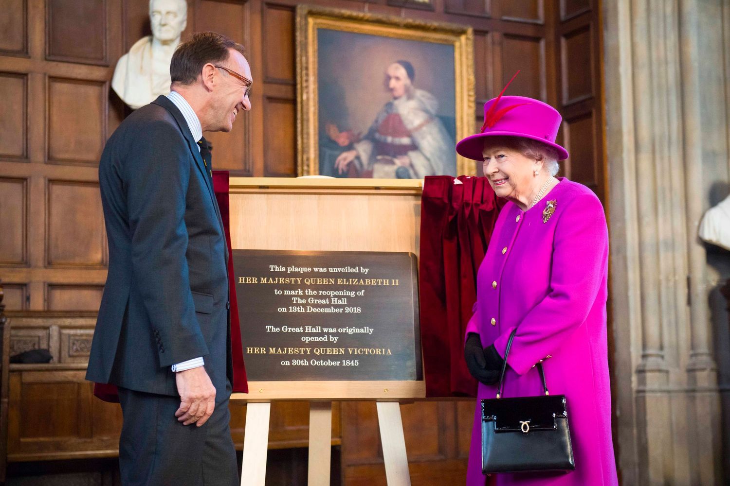 Formal ceremony in wood-paneled room with royal portraits and decorative elements. London Event Photographer