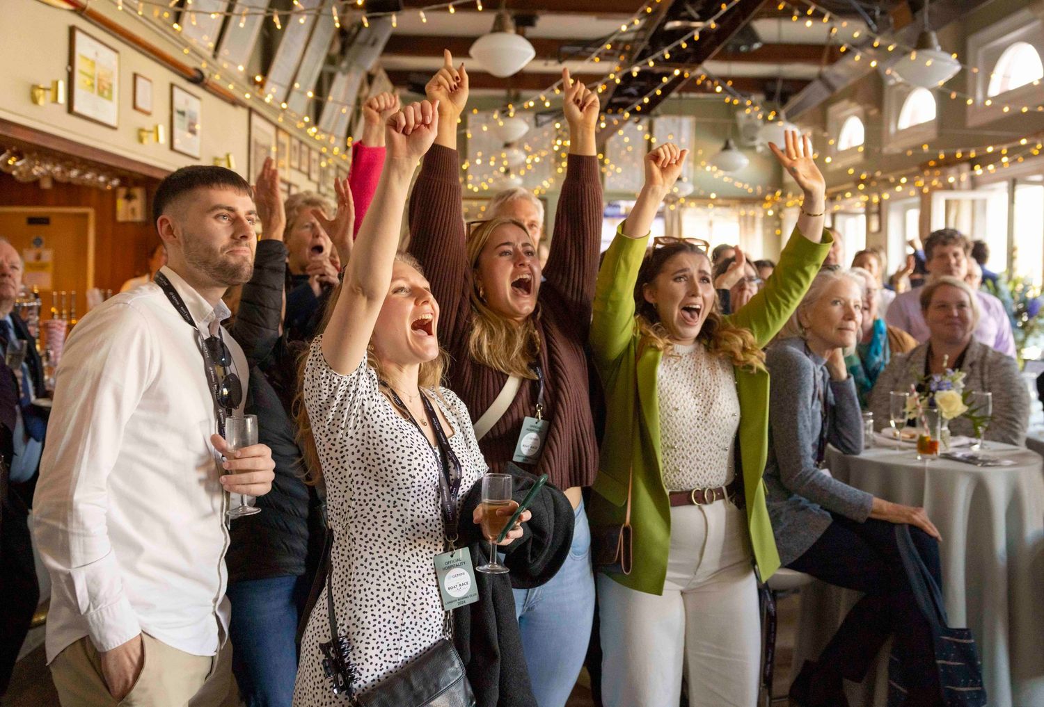 Excited audience members cheering and raising their hands at an indoor event venue. London Event Photographer