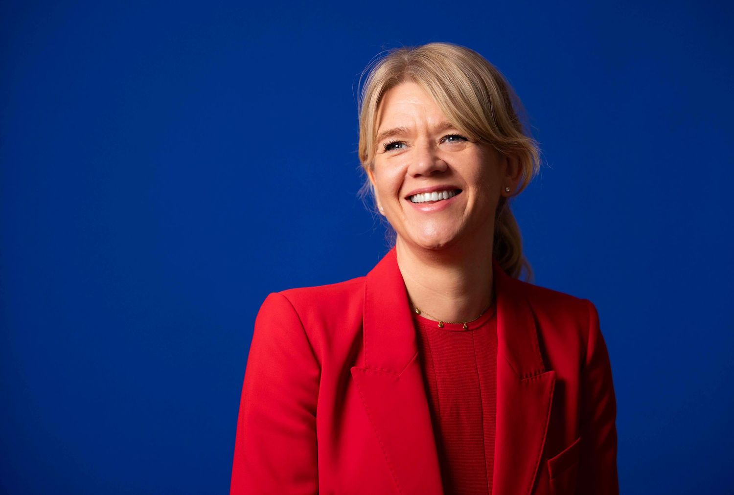 Portrait series against blue background wearing bright red blazer with confident expressions. London Event Photographer