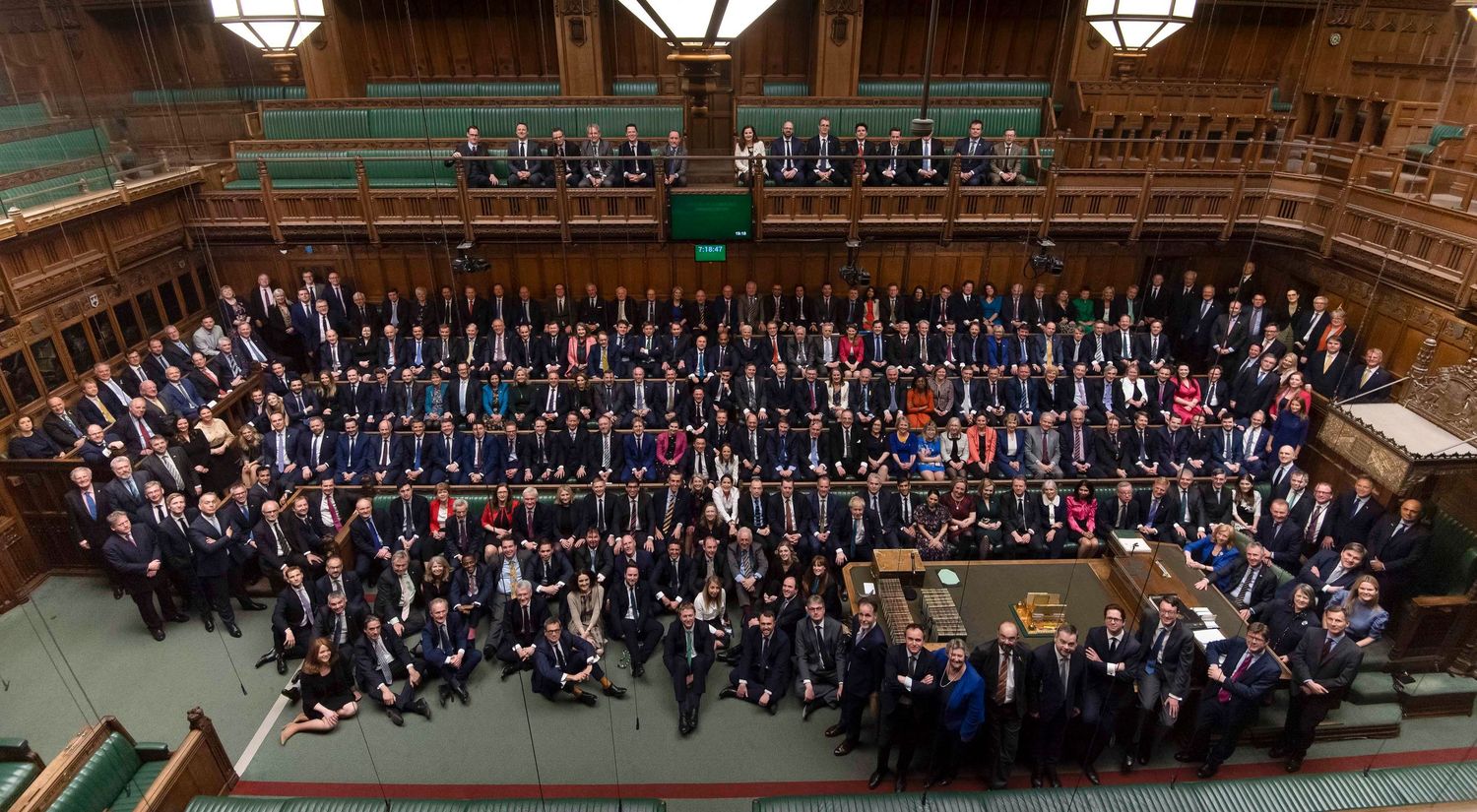 Large formal group photo of attendees arranged in rows inside an ornate concert hall or auditorium. London Event Photographer