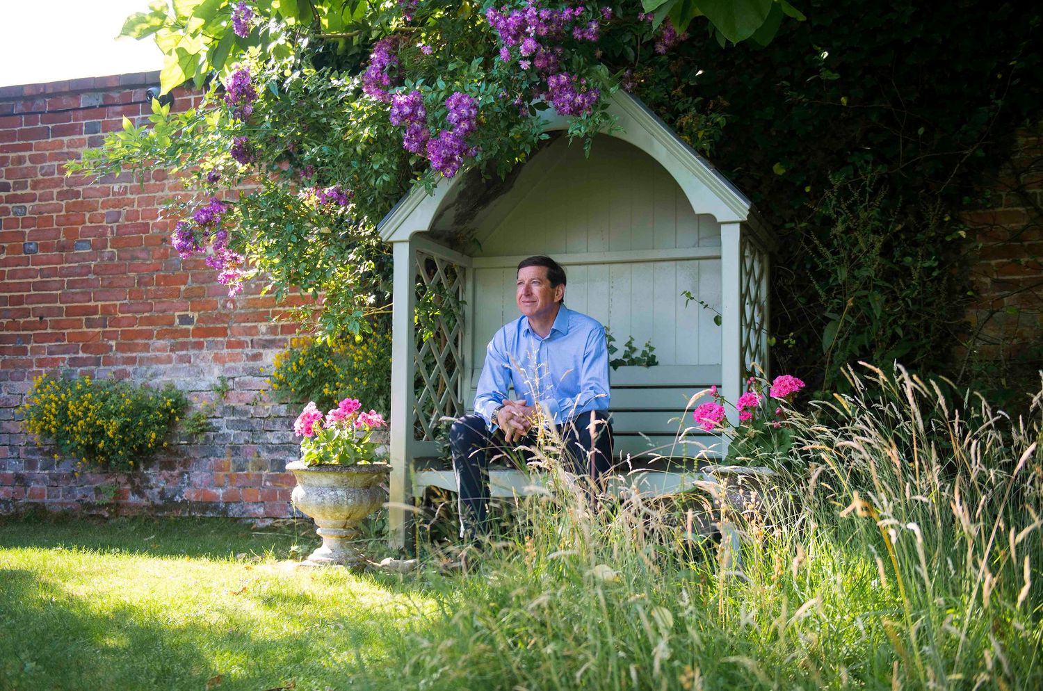 Garden scene with brick wall, flowering plants, and white garden structure. London Event Photographer