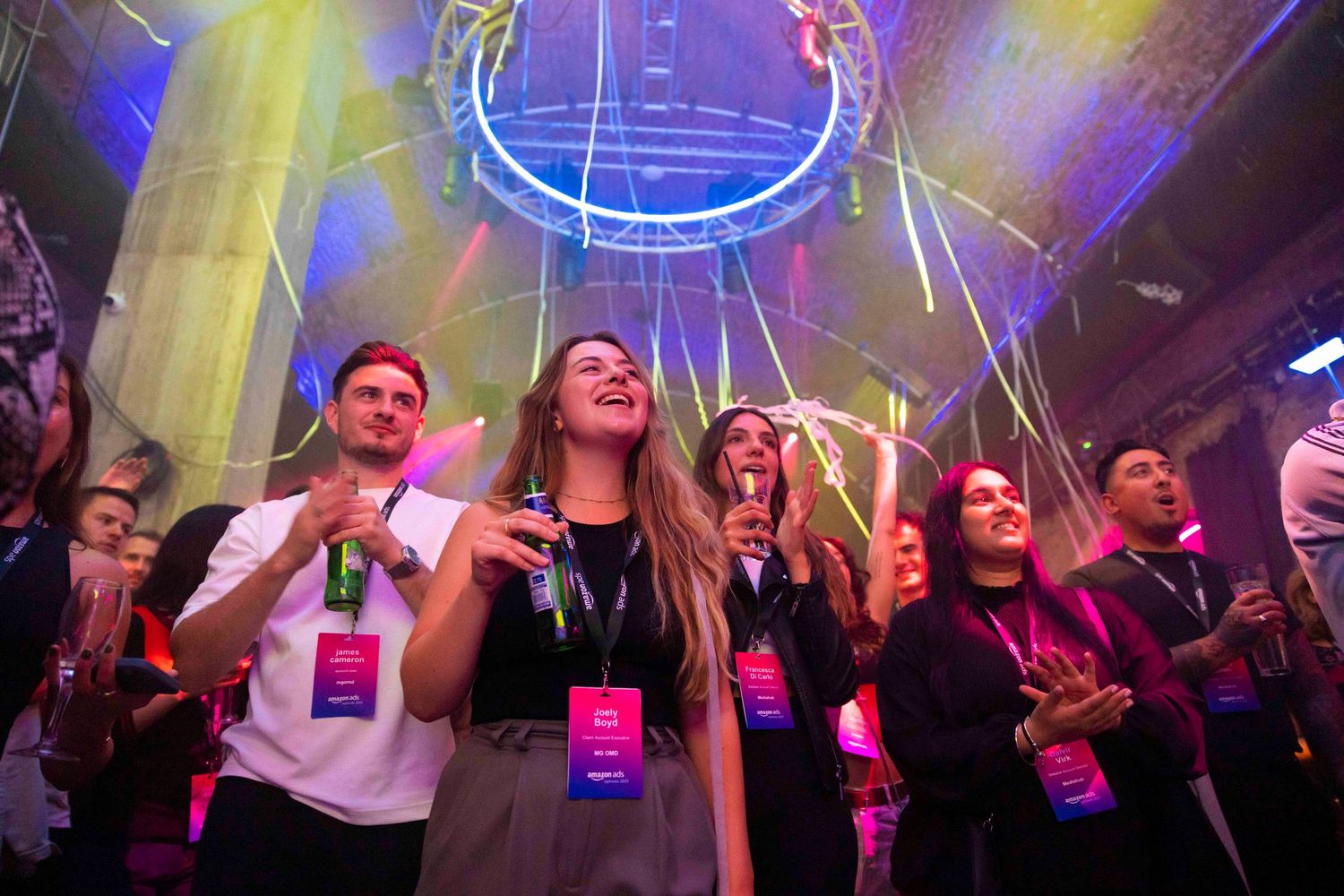Conference attendees holding illuminated devices during event with colorful stage lighting. London Event Photographer