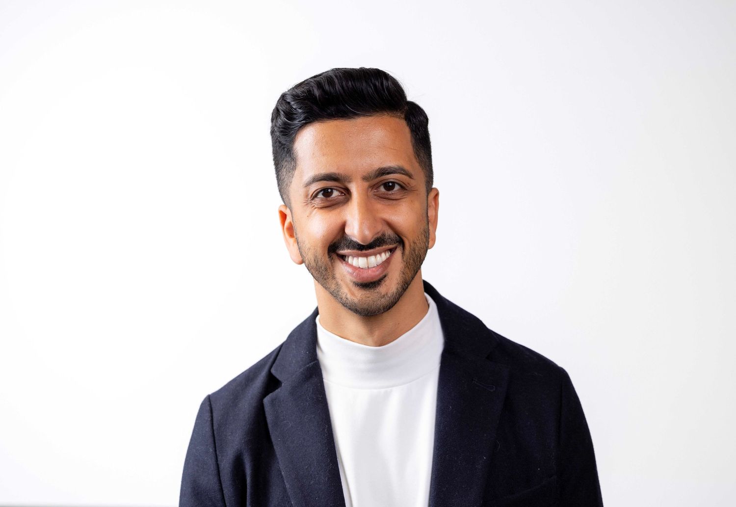 Professional headshots showing warm smile against white background in dark suit in london office. London Event Photographer