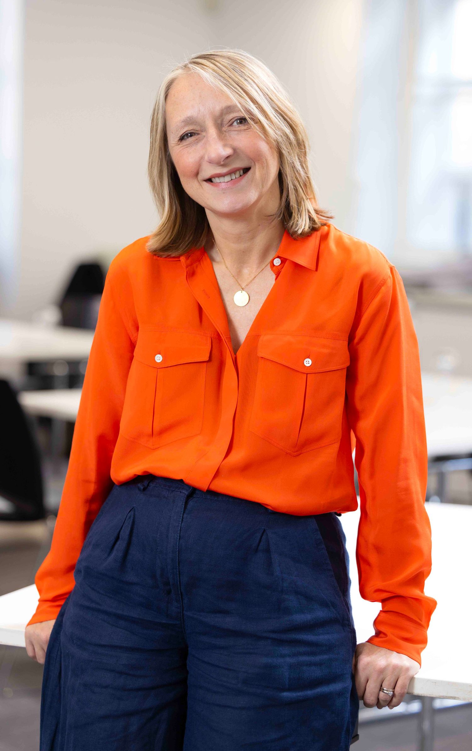 Professional portrait series showing a woman in bright orange blouse and navy pants against white background.  London Event Photographer