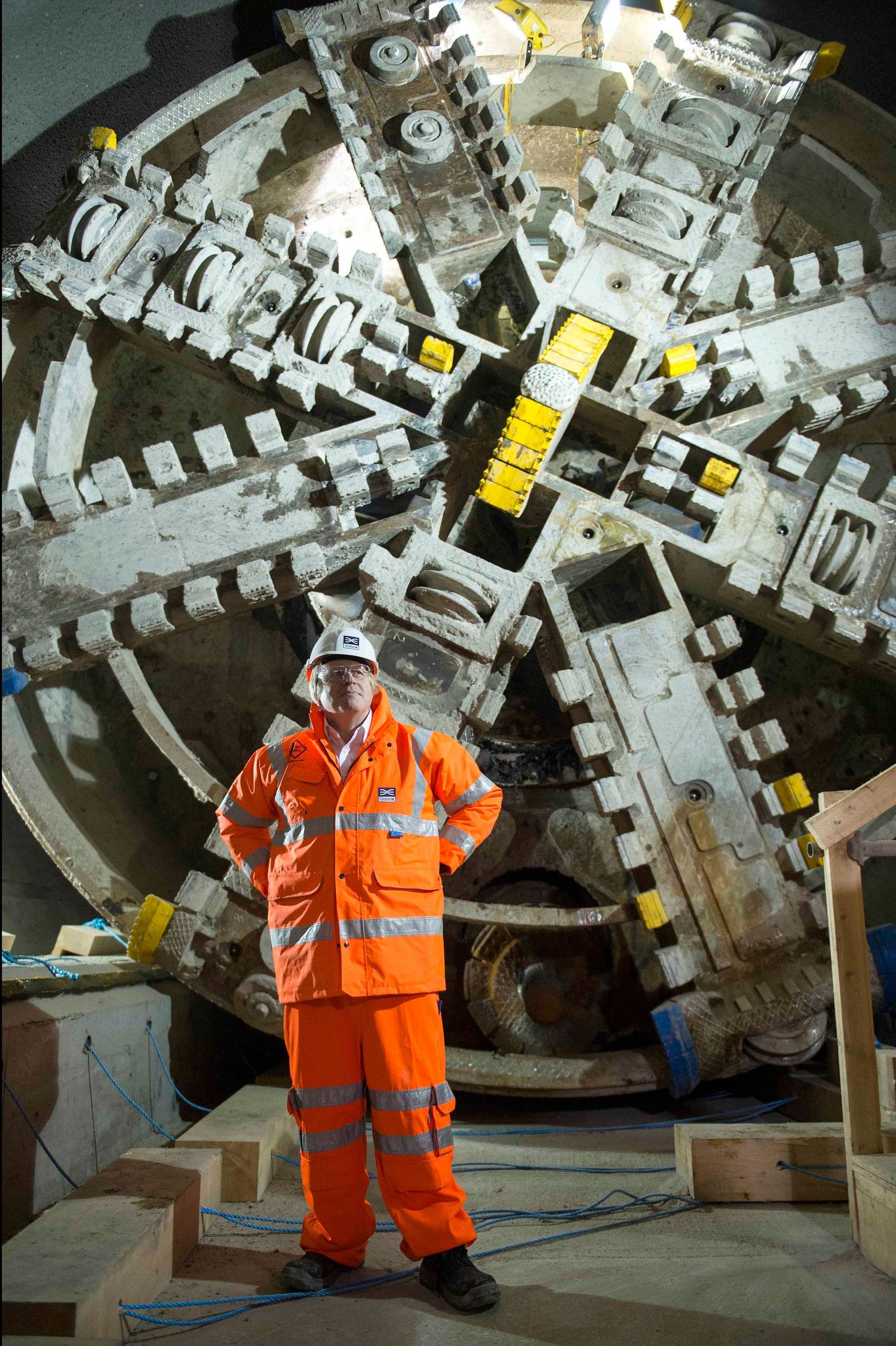 Boris Johnson in orange safety gear standing beside large industrial tunnel boring equipment for the Elizabeth Line.  London Event and confe