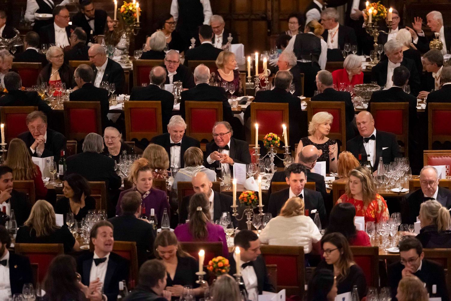 Large formal dinner gathering in an elegant banquet hall with tables of guests and glowing candelabras. London Event Photographer