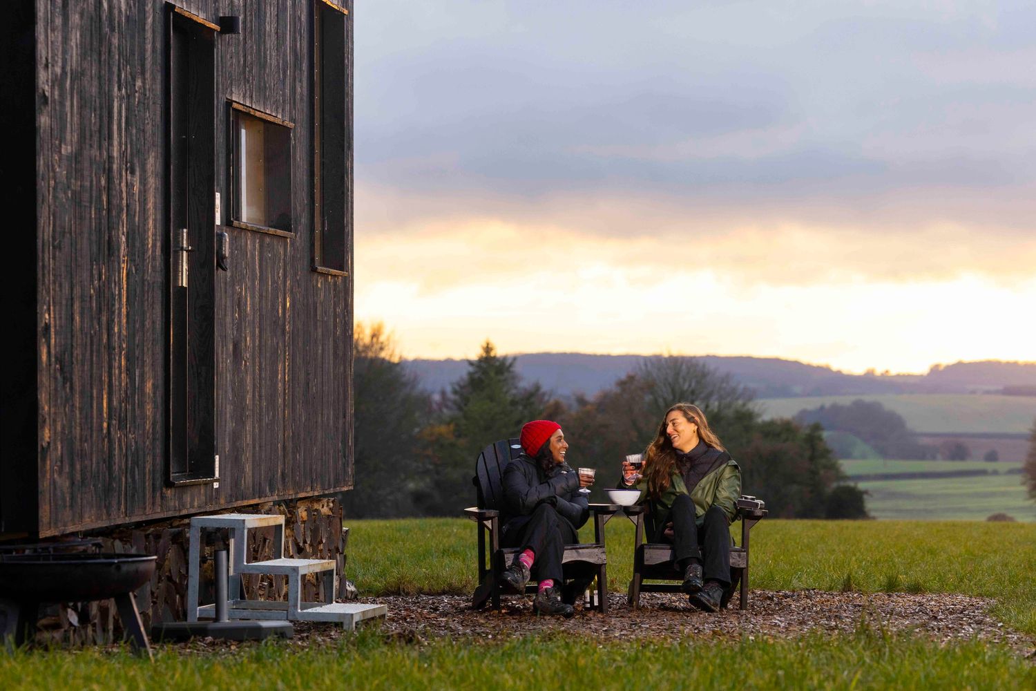 Rustic wooden barn structures in a rural landscape at sunset with mountains in the background. London Event Photographer