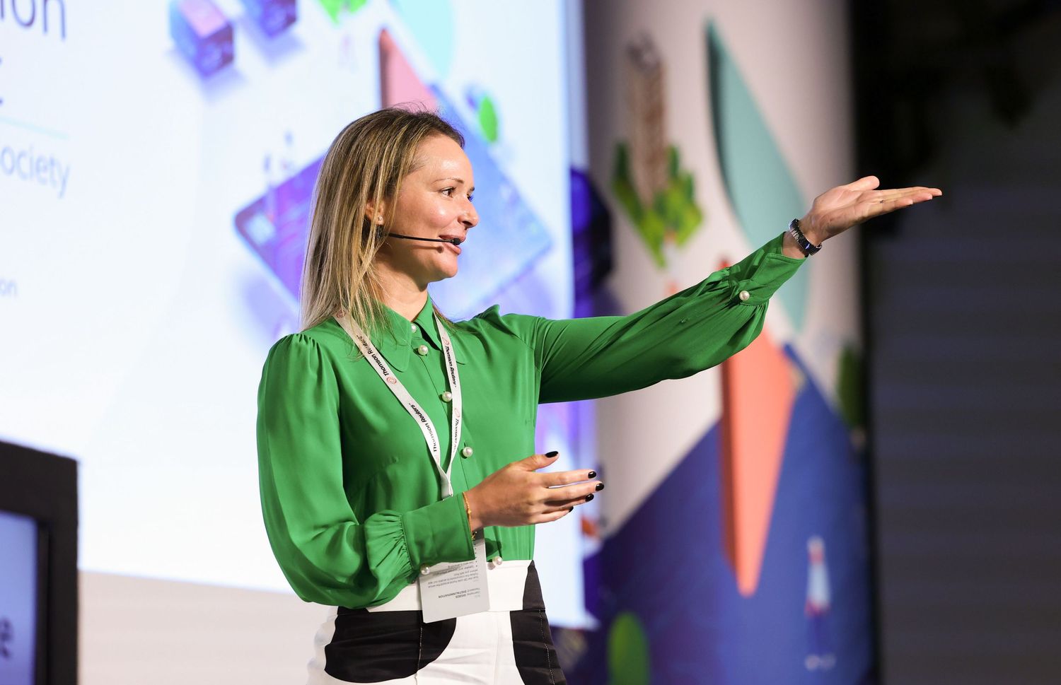 Presenter in bright green jacket gesturing during a stage presentation. London Event Photographer