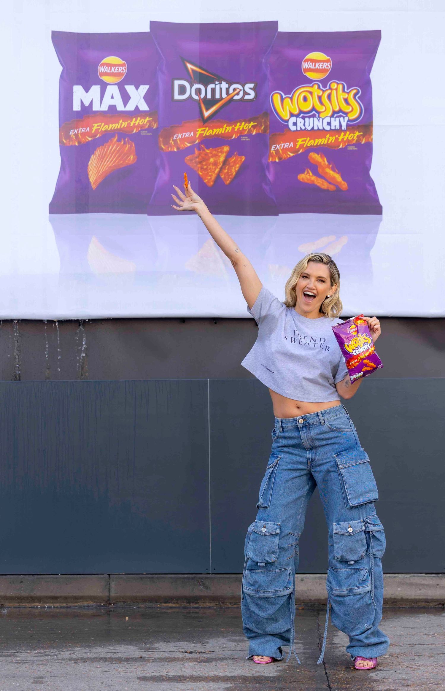 Person posing with snack bags in front of large Doritos advertisement display. London Event Photographer