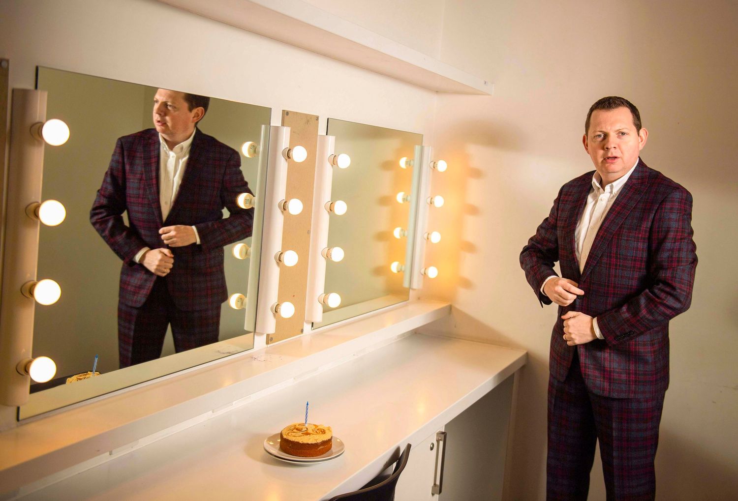 Dressing room mirror with vanity lights and formal attire visible in the reflection. London Event Photographer