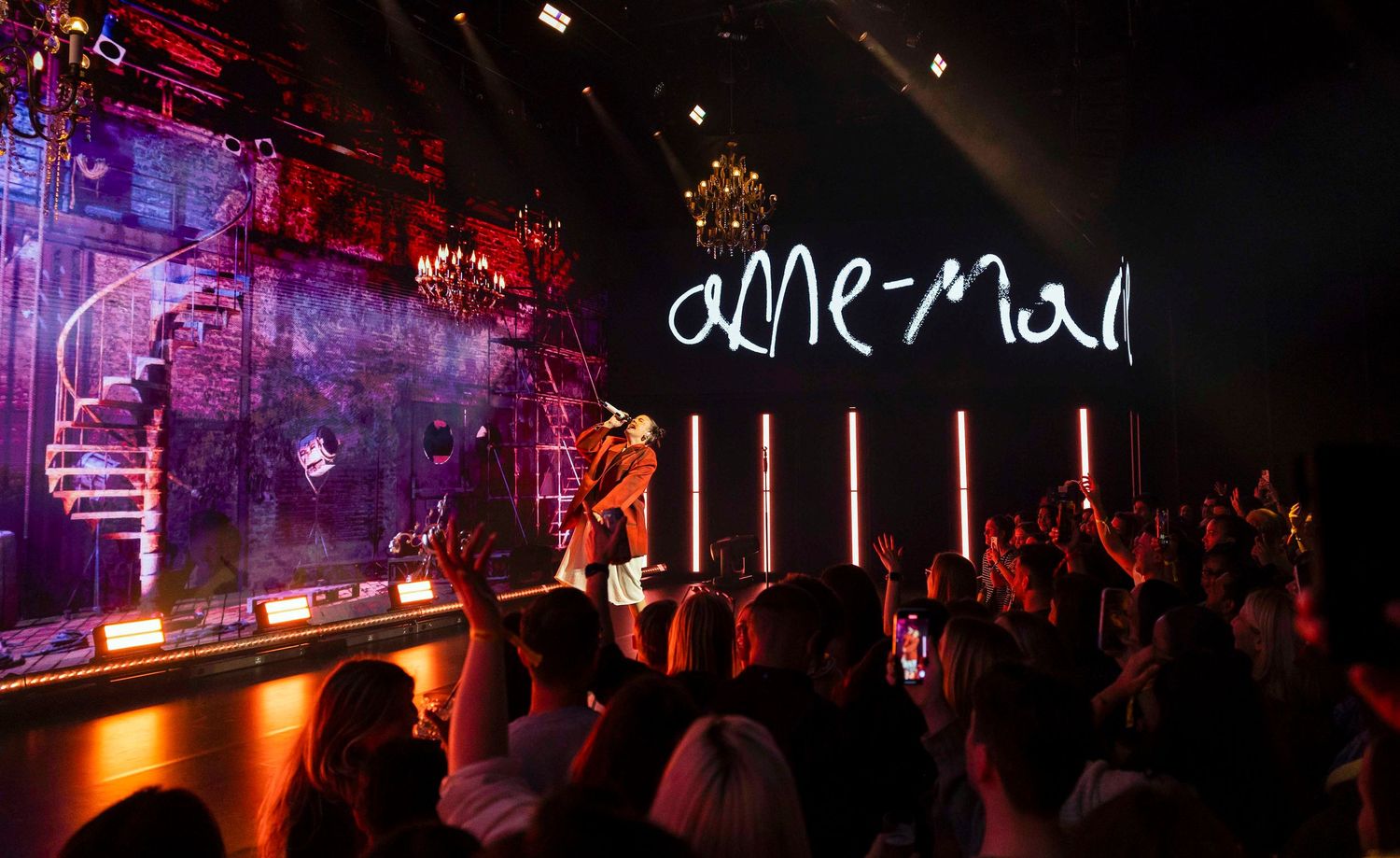 Dark venue with red lighting effects and crowd silhouettes. London Event Photographer
