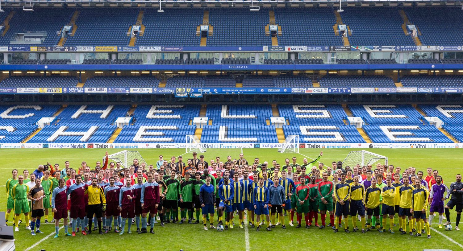 Soccer teams lined up on a blue stadium field for a group photo before a match. London Event Photographer
