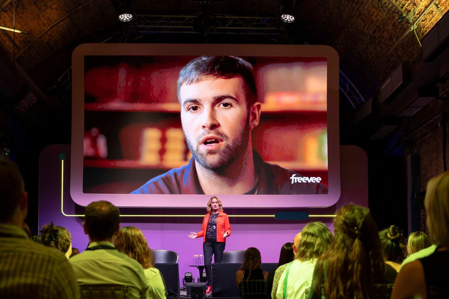 Tech conference presentation screen with purple lighting and audience silhouettes in foreground. London Event Photographer