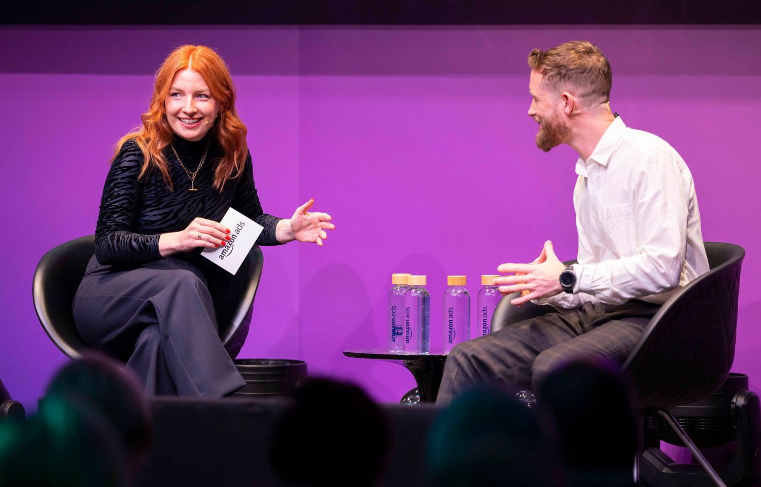 Speakers engaged in discussion on purple-lit stage at conference event. London Event Photographer