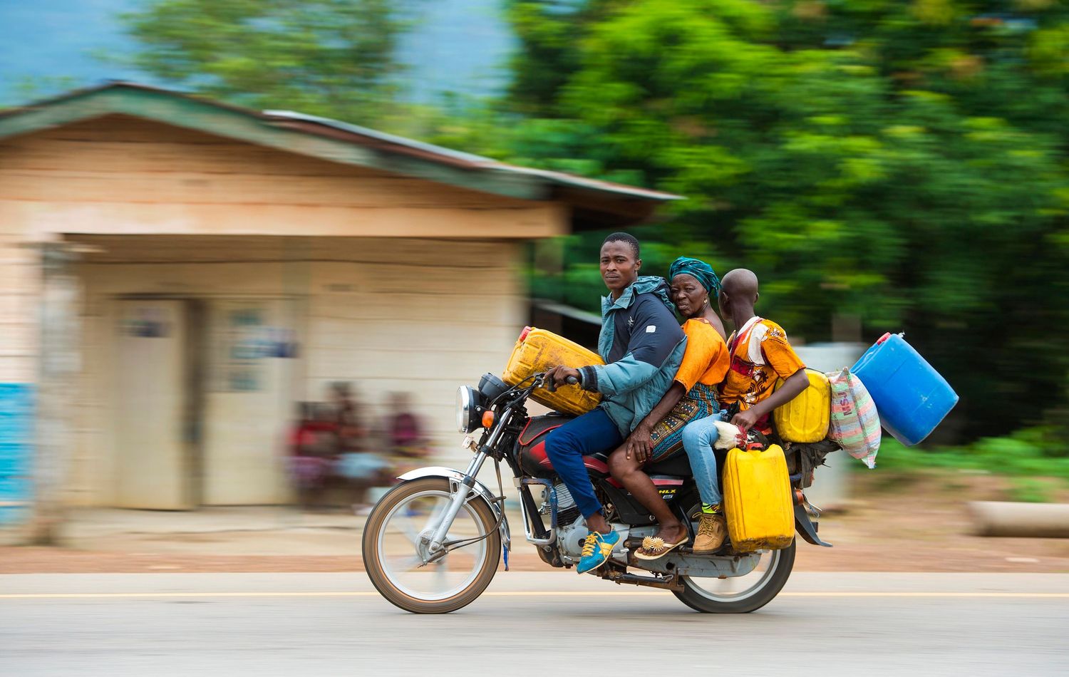 Blurred motion sequence of a motorcyclist riding with yellow luggage bags through a rural area. London Event Photographer