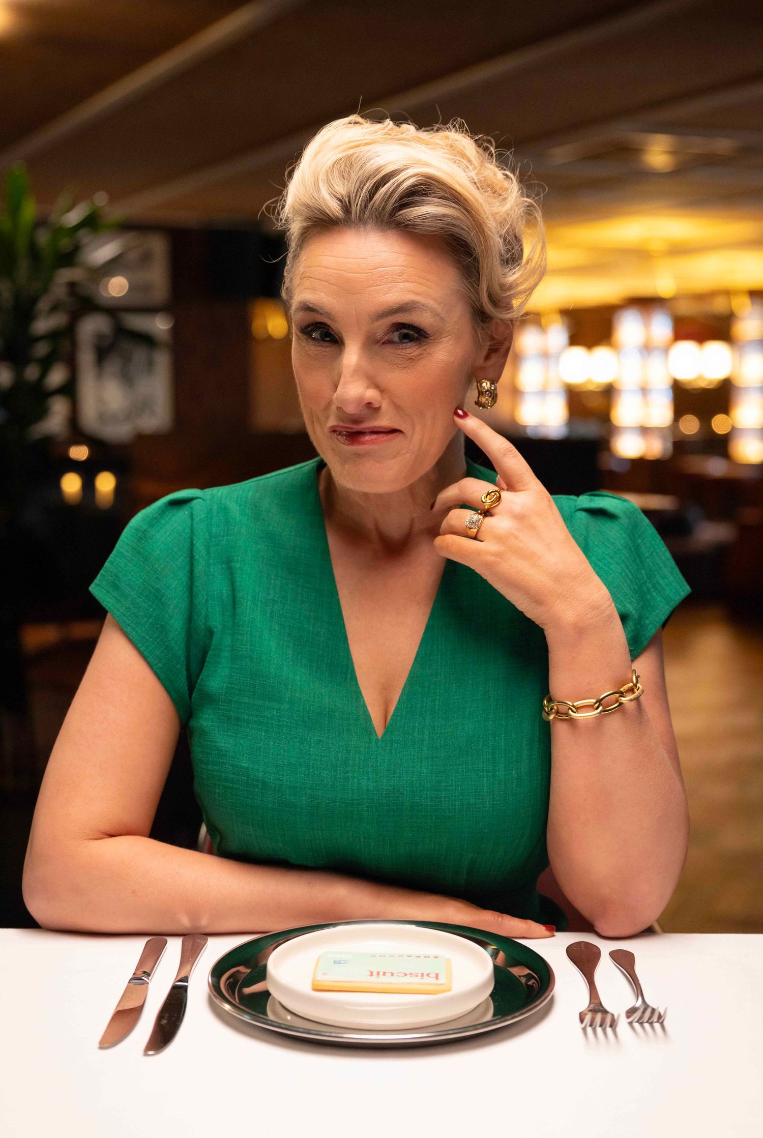 Person in green dress sits at restaurant table showing various expressions in sequence. London Event Photographer