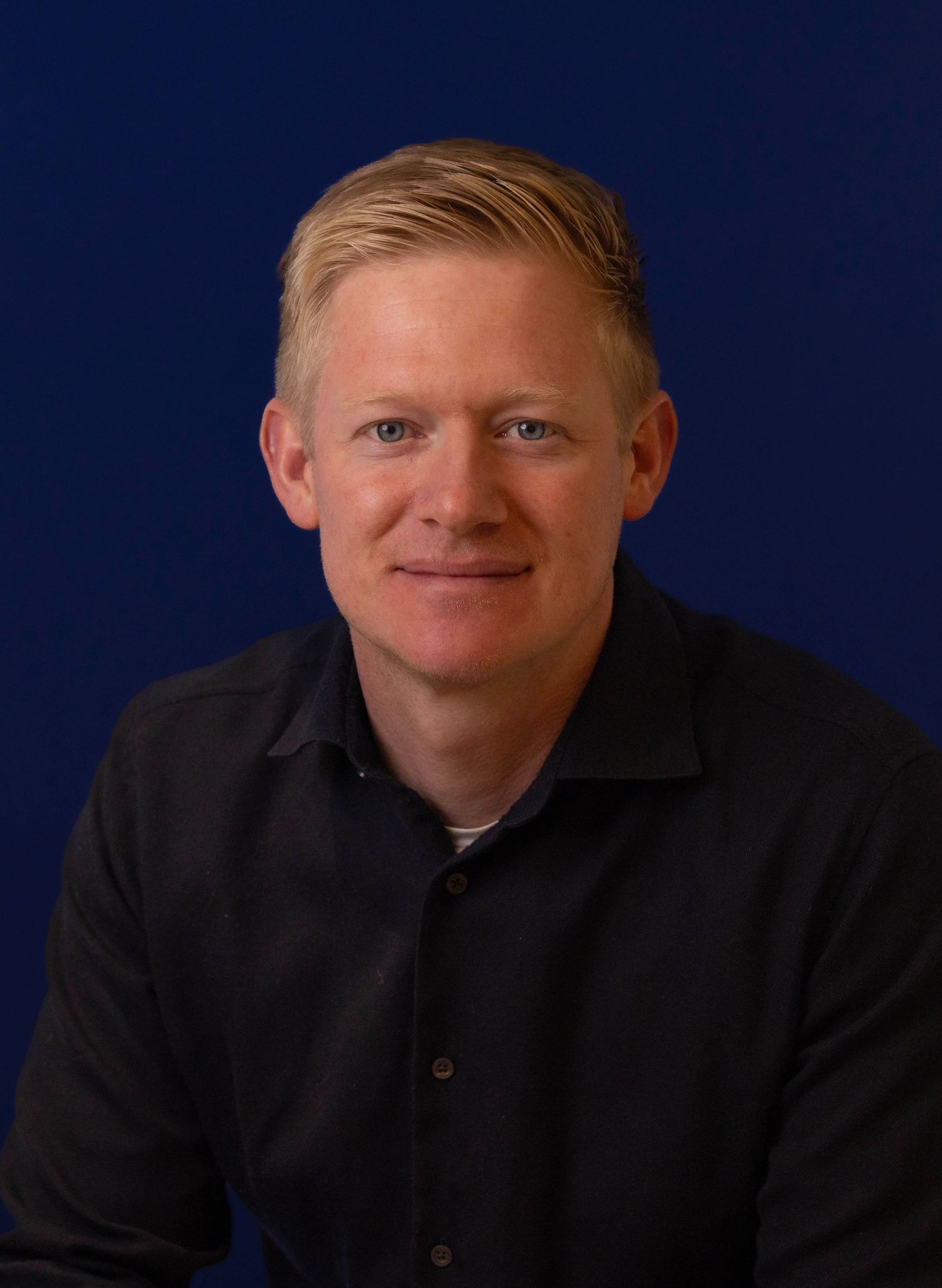 Portrait series showing casual professional poses in dark clothing against navy backdrop.  London Event and conference Photographer