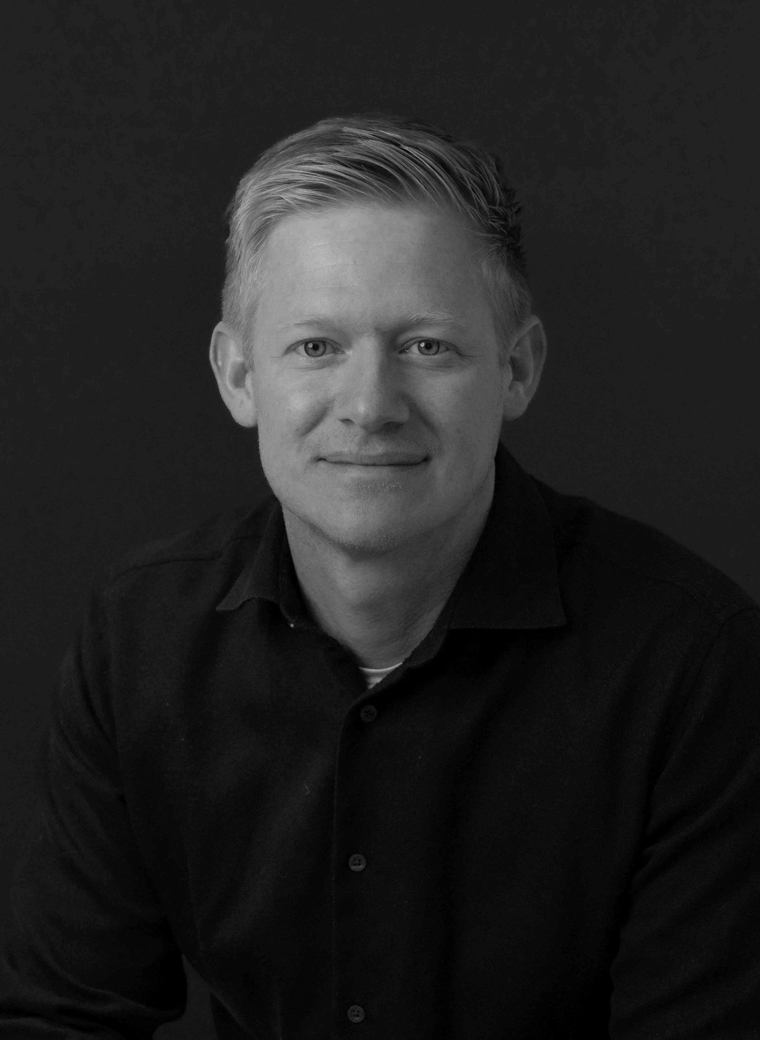 Black and white portrait series showing different expressions in dramatic lighting against dark background.