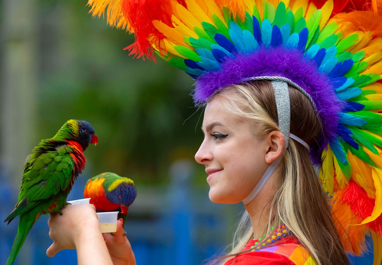 Colorful feathered headdress display with vibrant rainbow plumes against blue sky. London Event Photographer
