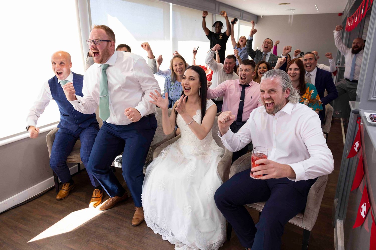 Wedding celebration scene with guests cheering in bright indoor venue. London Event Photographer