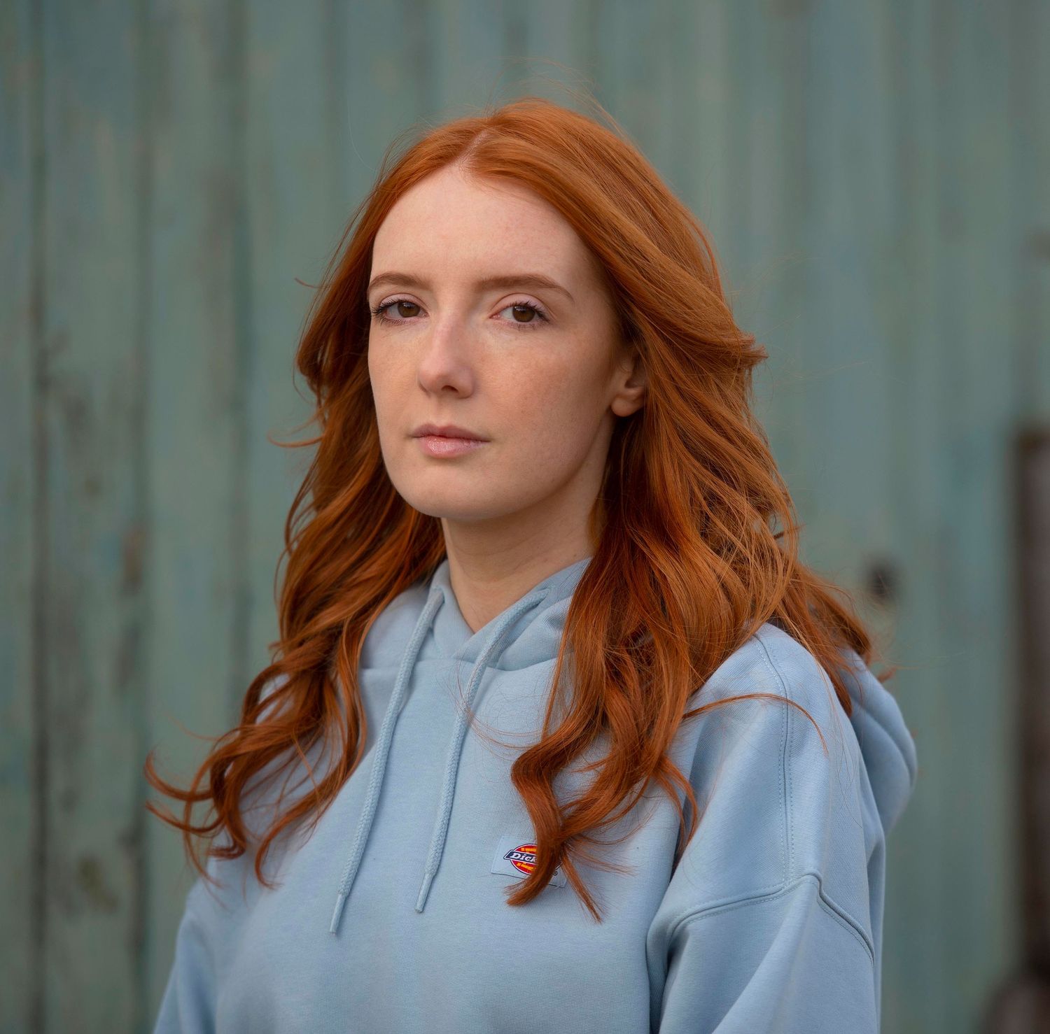 Portrait series of someone with flowing red hair wearing a light blue hoodie. London Event Photographer