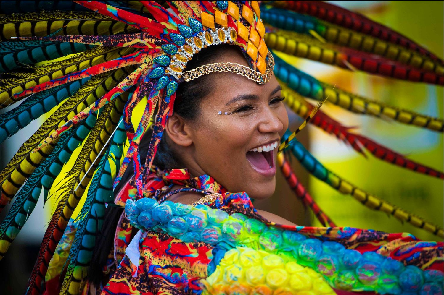 Vibrant carnival dancers in colorful feathered headdresses performing during a festive celebration. London Event Photographer