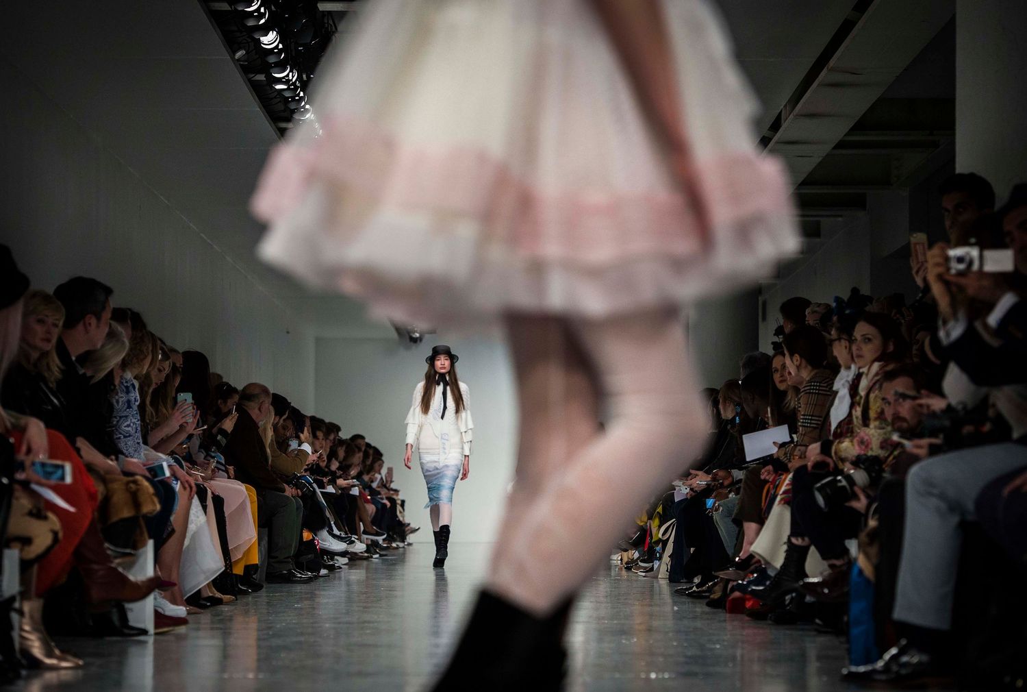 Fashion models walk the runway showcasing flowing pink tulle dresses in a minimalist gallery space. London Event Photographer