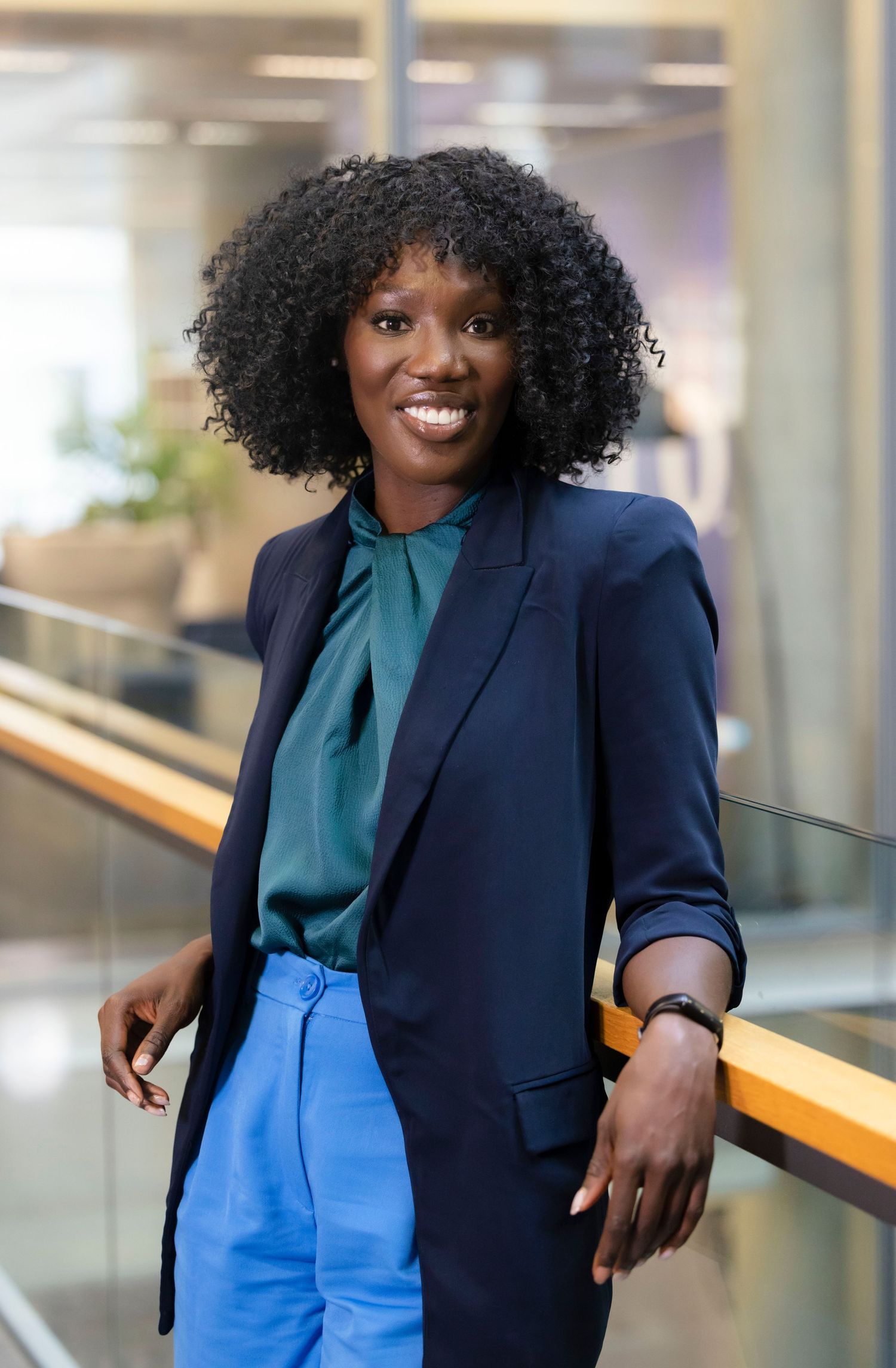 Professional woman in navy blazer and blue pants walking through modern office building. London Event Photographer