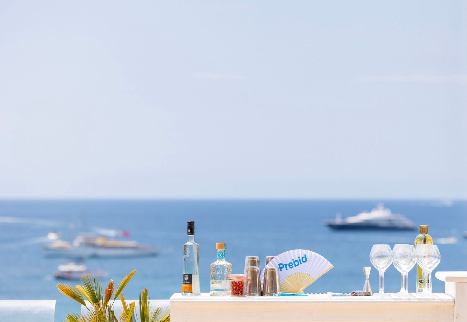 Tranquil beach scene with white picket fence and boats visible on the ocean horizon. London Event Photographer