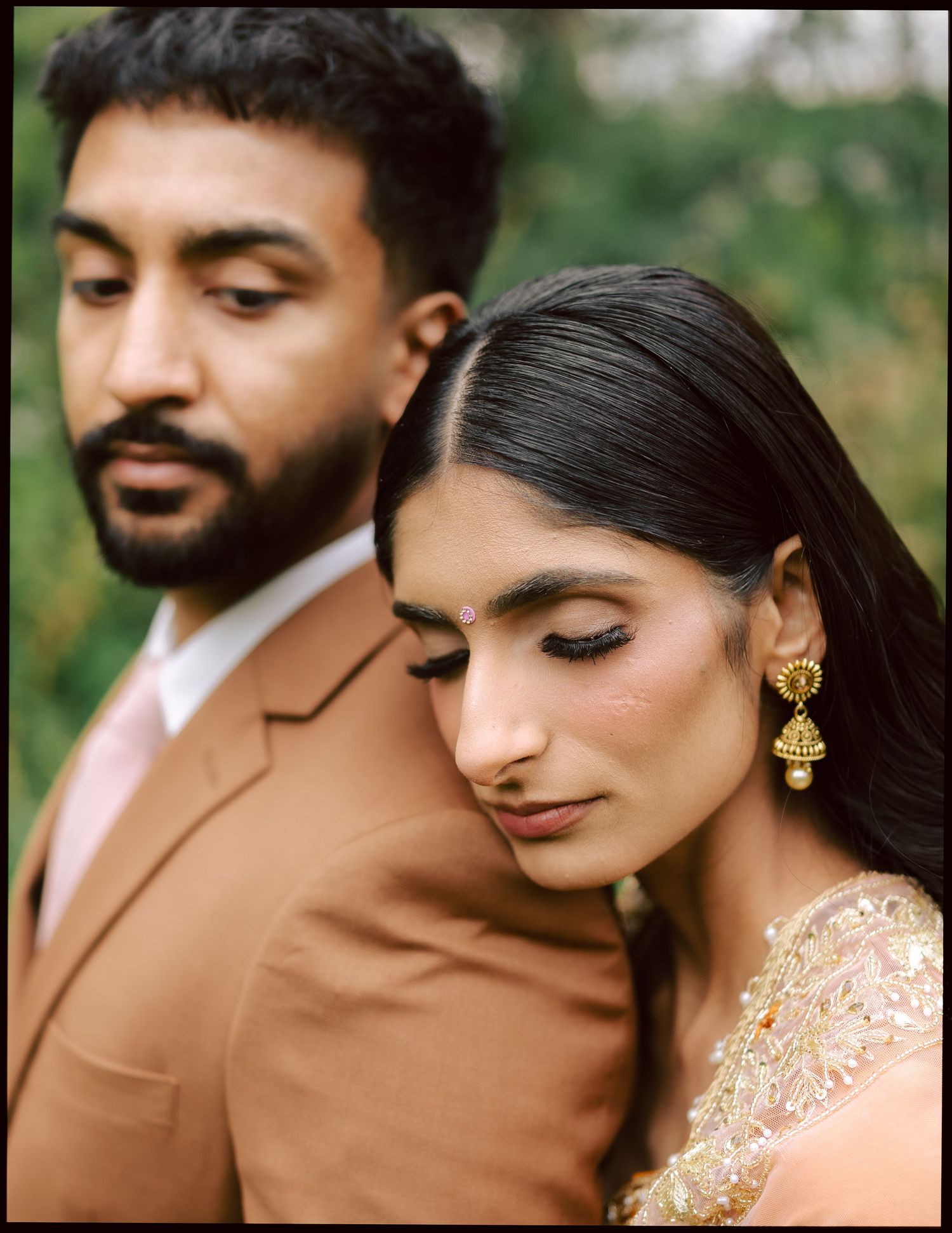 Close-up of South Asian bride and groom in traditional wedding attire with gold jhumka earrings.