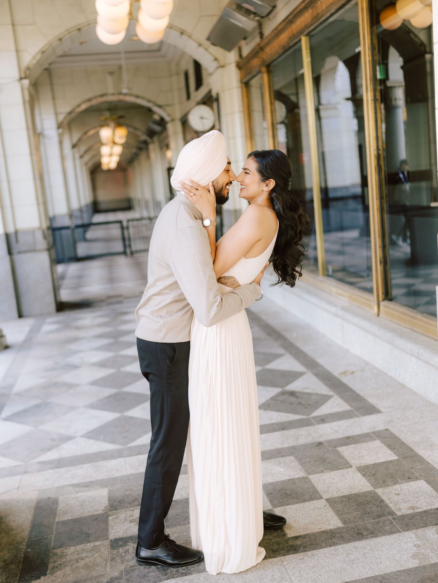 Couple shares a tender nose-to-nose moment in a classic arched corridor engagement photo.