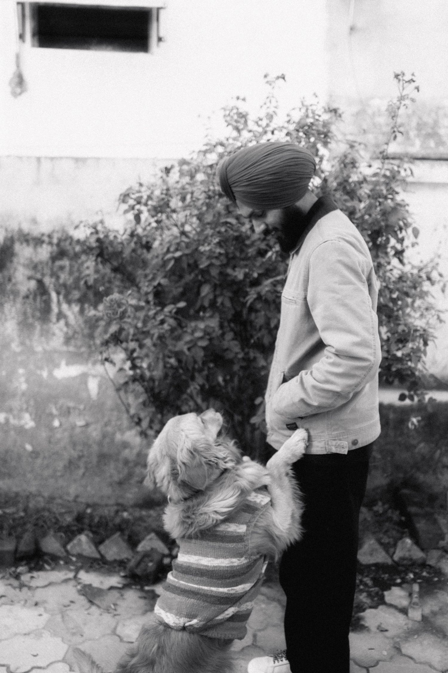 Black and white photo of Sikh man in turban interacting warmly with a small child outdoors.